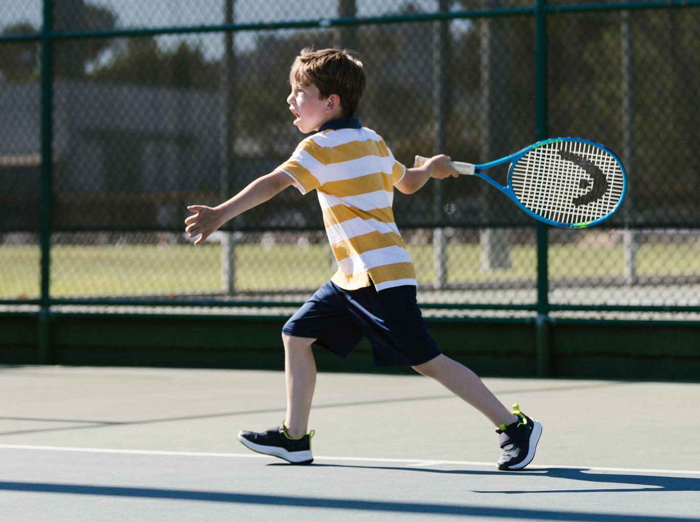 A boy hitting a forehand on a tennis court